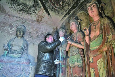 在麦积山石窟第11窟，修复师对塑像破损处进行加固处理。 新华社发