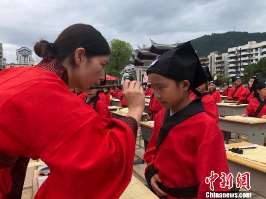 　资料图：在“点朱启智”环节中，先生在学童的额心点上朱砂，寓意孩子从此开启智慧，目明心亮