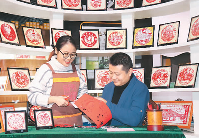 贵州省级非遗传承人李跃（右）在遵义老城红军街“剪纸坊”指导游客体验红色文化剪纸。朱大军摄（人民图片）