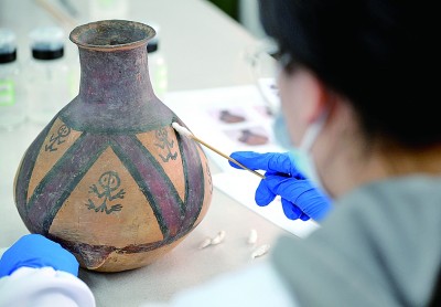 在中国文化遗产研究院陶瓷金属文物修复室内，专业技术人员在对彩陶文物进行修复。新华社发