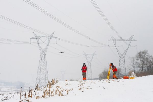 国网本溪供电公司输电运维人员用全站仪观察500千伏白徐线雪后运行状态。 姜云峰 摄